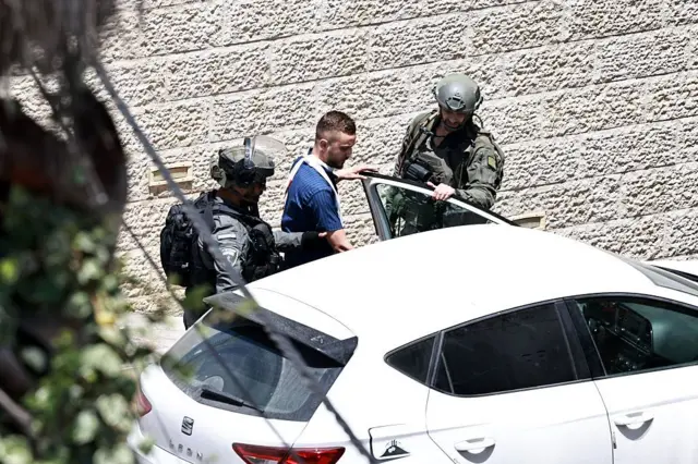 جنود الجيش الإسرائيلي يعتقلون رجلاً أثناء مداهمة محل صرافة في رام الله بالضفة الغربية المحتلة في 27 مايو 2025.