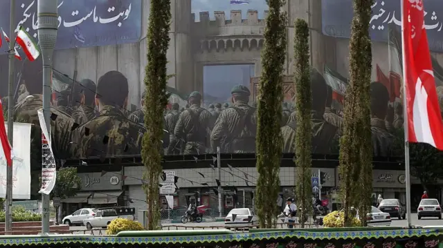 جدارية ضخمة تُصوّر أفراداً من الجيش على زاوية مبنى في طهران. أسفلها، تمر سيارات في الشارع.