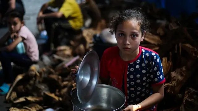 أطفال فلسطينيون ينتظرون الحصول على الطعام عند نقطة توزيع في النصيرات، وسط قطاع غزة
