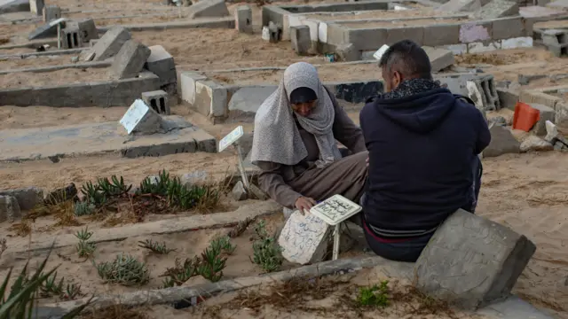 عائلة فلسطينية تزور قبور أقاربها في مقبرة في عيد الأضحى، بخان يونس، جنوب قطاع غزة، 6 يونيو/حزيران 2025.