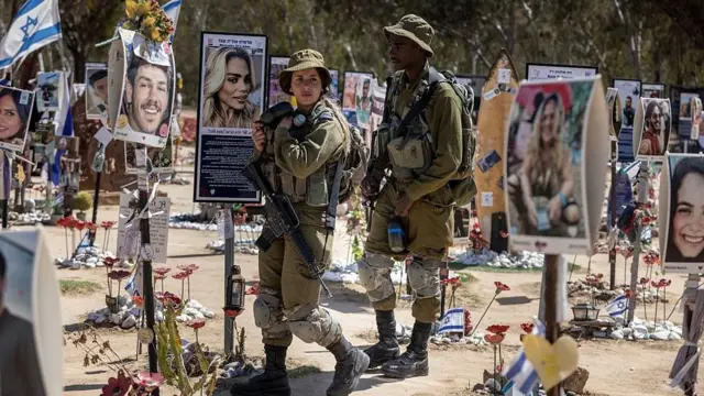 أفراد من الجيش الإسرائيلي يسيرون بين النصب التذكارية لأولئك الذين قتلوا في موقع مهرجان نوفا للموسيقى في أكتوبر 2023
