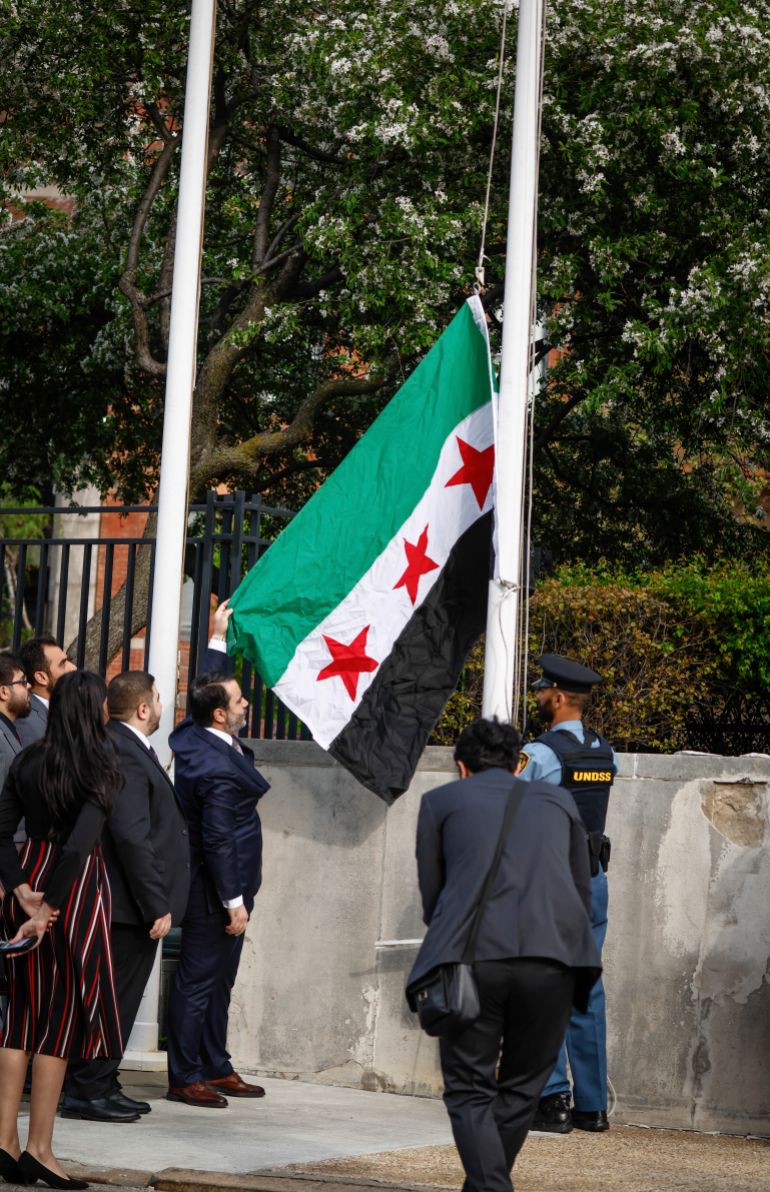 Syria's Foreign Minister Asaad Al-Shibani holds the Syrian Flag during a ceremony where the Syrian flag was added to the 100 flags flying in line at United Nations Headquarters on Friday, April 25, 2025. (AP Photo/Kena Betancur)