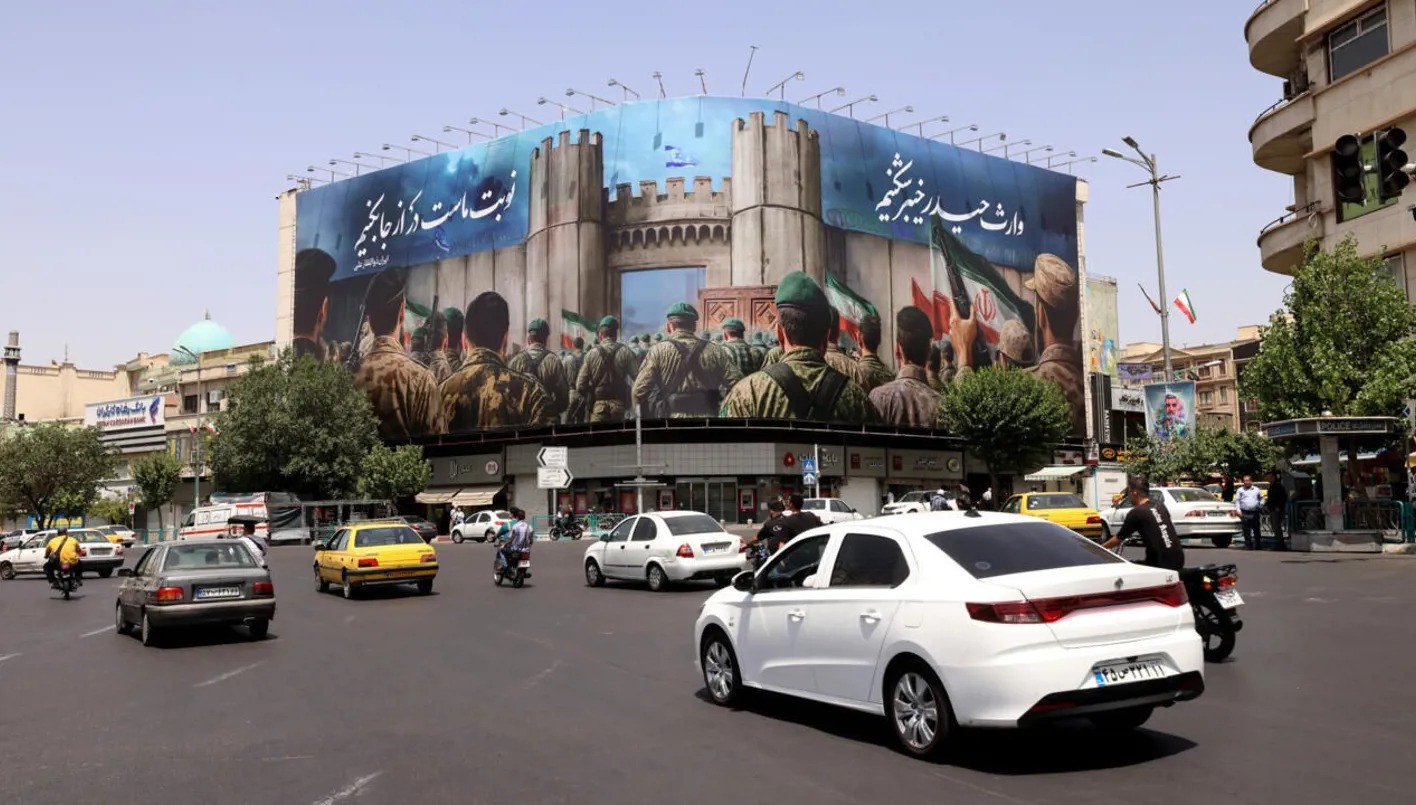 سيارات تسير بجوار لافتة ضخمة في ساحة انقلاب (الثورة)، طهران، 24 يونيو 2025 (أ ف ب)