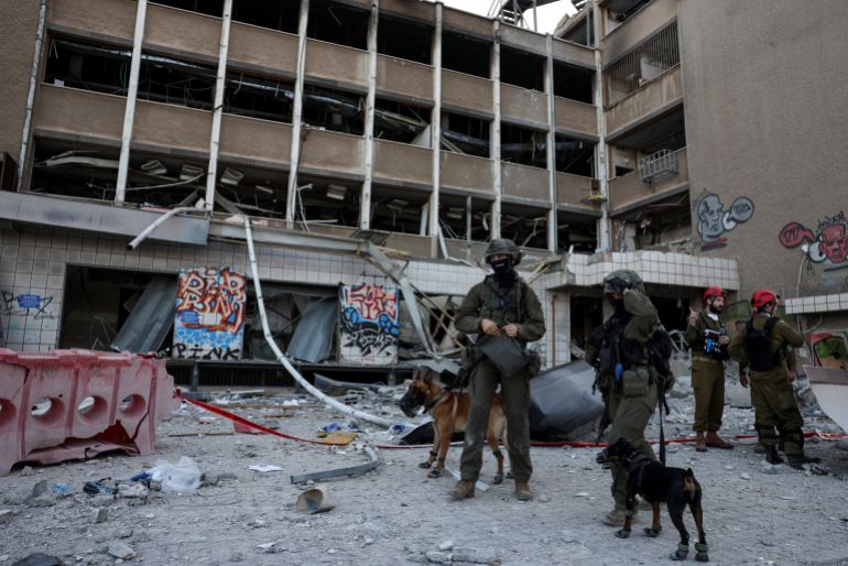 Emergency personnel hold dogs on a leash at an impact site following Iran's missile strike on Israel, amid the Iran-Israel conflict, in Haifa, Israel, June 20, 2025. REUTERS/Florion Goga
