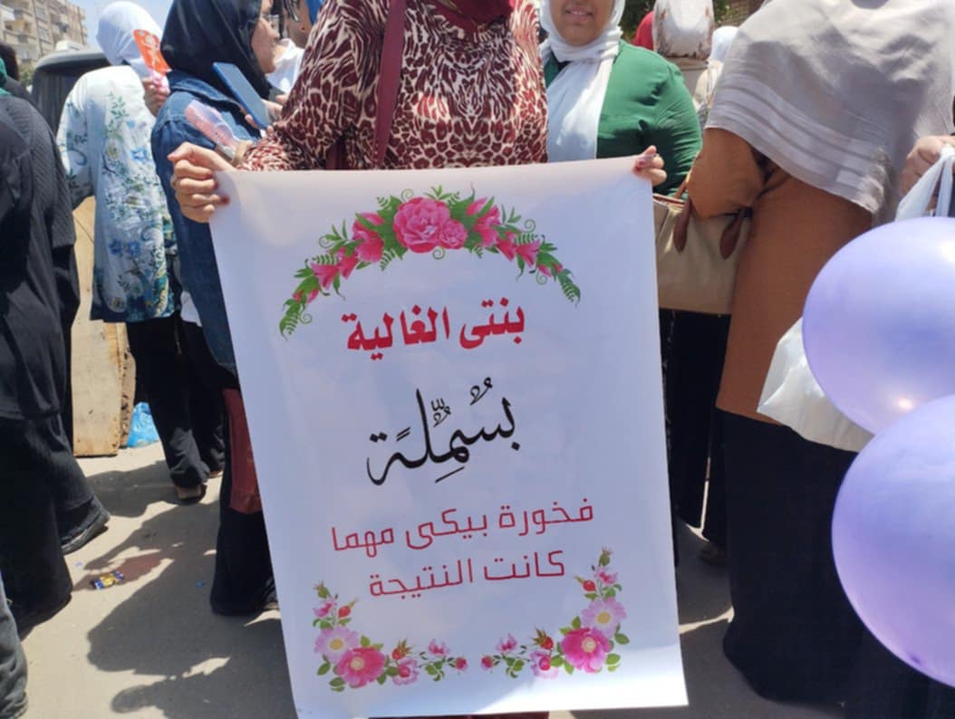 أم تدعم ابنتها طالبة ثانوية عامة أمام مدرسة بالإسكندرية