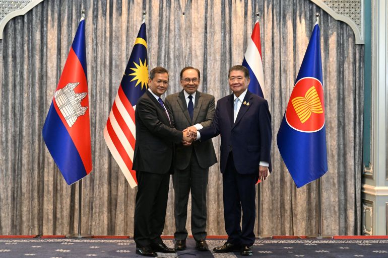 Malaysia's Prime Minister Anwar Ibrahim (C), Cambodia's Prime Minister Hun Manet (L) and Thailand's acting Prime Minister Phumtham Wechayachai (R) pose for photos as they shake hands following a press conference after talks on a possible ceasefire between Thailand and Cambodia in Putrajaya on July 28, 2025.