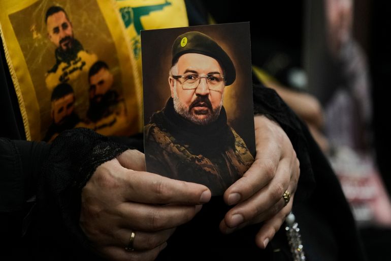 A woman holds a photo of top Hezbollah commander Fouad Shukur, who was killed in an Israeli airstrike, during a commemoration marking the first anniversary of his death in Dahiyeh, a southern suburb of Beirut, Lebanon, Wednesday, July 30, 2025. (AP Photo/Bilal Hussein)