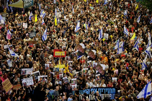 حشود من المتظاهرين في تل أبيب ليلاً يحملون يافطات وأعلام إسرائيل