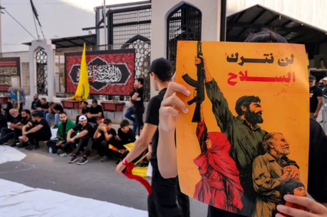صورة من مظاهرة مؤيدة لحزب الله ويبدو فيها شخص يحمل لافتة مكتوب عليها: "لن نترك السلاح".