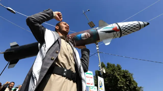 رجل يمني يحمل صاروخاً في مسيرة لدعم غزة داخل اليمن.