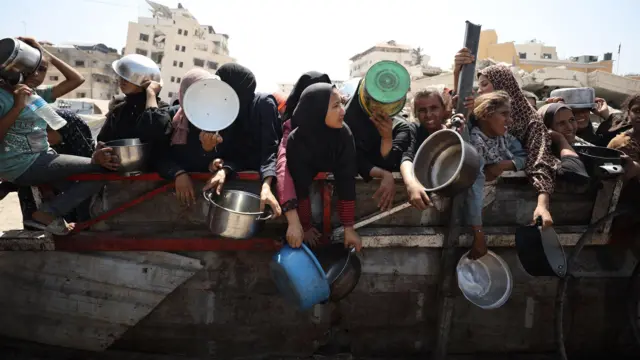 يتلقى فلسطينيون، بمن فيهم أطفال، وجبات ساخنة، توزعها منظمات خيرية، في ظل معاناة الناس من أجل الحصول على الغذاء بسبب الحصار الغذائي الإسرائيلي في مدينة غزة، غزة، في 23 أغسطس/آب 2025. 