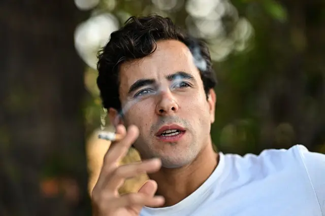 مصارع الثيران الفرنسي كارلوس أولسينا يدخن سيجارة في فندقه قبل مصارعة الثيران المسائية كجزء من مهرجان بيزييه في جنوب غرب فرنسا، في 14 أغسطس/آب 2025.
