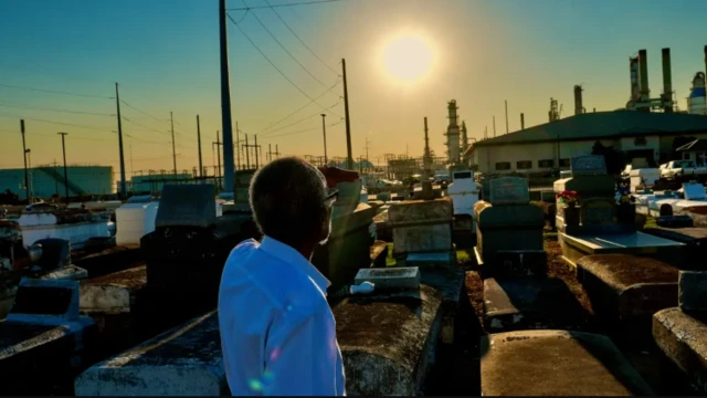 رجل ذو بشرة سوداء يتطلع إلى مداخن أحد المصانع 