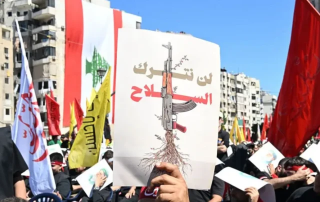 صور تظهر مُحتجين في لبنان يحملون لافتة ًكُتب عليها "لن نترك السلاح".