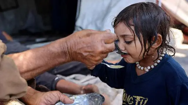  فلسطيني يطعم حساء العدس لطفلة في حي الدرج بمدينة غزة في 3 أغسطس اب 2025