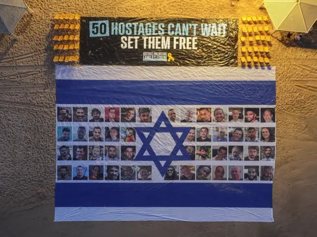 صورة للعلم الإسرائيلي وبداخله صور الرهائن الذين لا يزالون محتجزين لدى حماس مقابل القنصلية الأمريكية في تل أبيب، إسرائيل، 26 أغسطس/آب 2025.