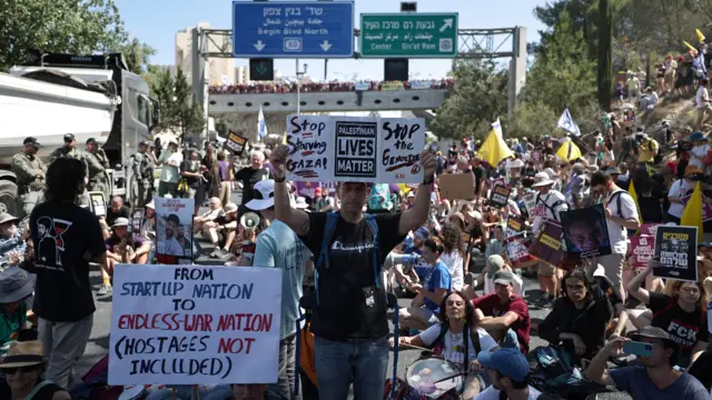 يحمل المتظاهرون لافتات أثناء إغلاقهم طريقاً رئيسياً في القدس، كجزء من إضراب للمطالبة بالإفراج الفوري عن الرهائن.