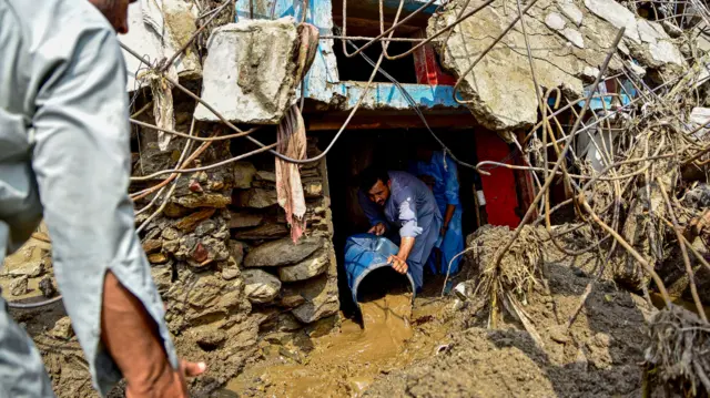 شخص يقوم بإزالة الوحل من داخل منزله المتضرر في ولاية خيبر باختونخوا في شمال باكستان