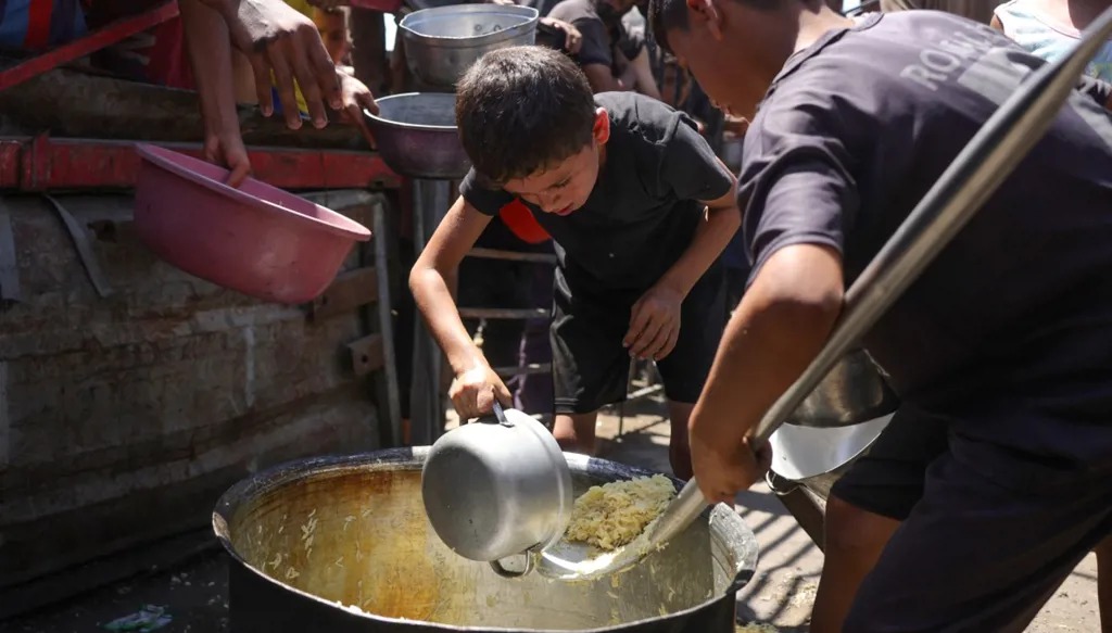 أطفال يقومون بتحضير حصة من الأرز يوزعها مطبخ خيري يقدم الطعام مجانا غرب مدينة غزة (أ ف ب).