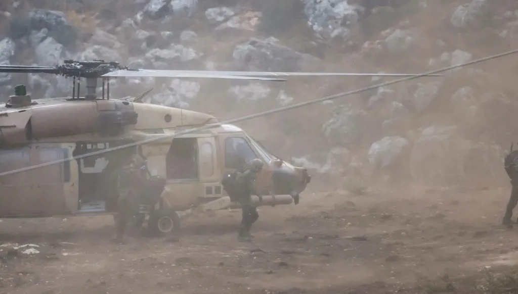 نود إسرائيليون إلى جانب مروحية عسكرية. (أ ف ب)