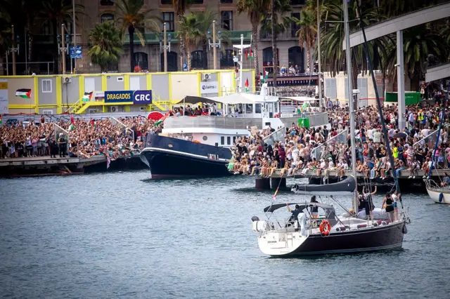 تجمع المئات في مول دي لا فوستا في برشلونة لتوديع أسطول الصمود العالمي المتجه إلى غزة، في 31 أغسطس/آب 2025. ورفعت عشرات القوارب الأعلام الفلسطينية.