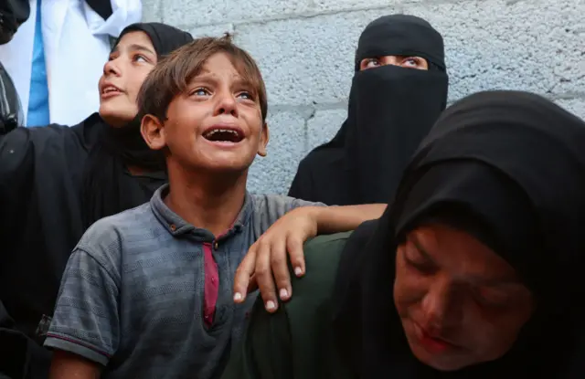 طفل ونساء يبكون خلال تشييع جنازة ذويهم الذين قُتلوا بنيران إسرائيلية أثناء محاولتهم تلقي المساعدة يوم الأحد، في مستشفى ناصر في خان يونس، جنوبي قطاع غزة في 1 سبتمبر/أيلول 2025.