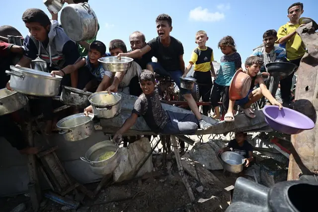 صورة بتاريخ  3 سبتمبر/أيلول في مدينة غزة، حيث أُُعلنت المجاعة ويظهر فلسطينيون يحملون أواني وأوعيةً، ويشكلون حشداً لتلقي مساعدات غذائية مقدمة من جمعية خيرية في المدينة.