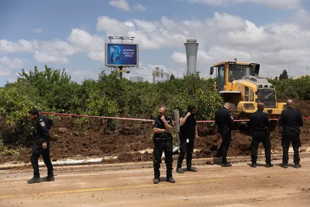 صورة أرشيفية بتاريح 4 مايو/أيار2025 لضباط شرطة يحرسون جراراً، يعمل في مكان حادث بعد أن أطلق الحوثيون صاروخاً باليستياً من اليمن بالقرب من مطار بن غوريون الدولي في تل أبيب بإسرائيل.