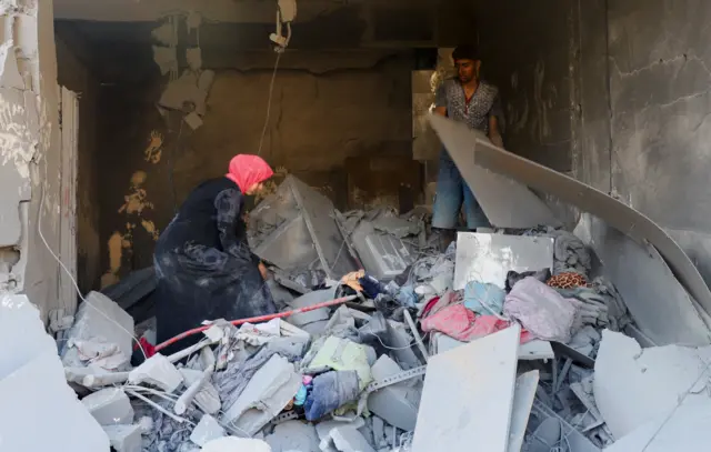 فلسطينيون يبحثون عن ضحايا في موقع غارة إسرائيلية على منزل في مدينة غزة