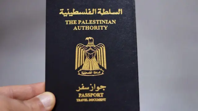 يد تمسك بجواز سفر يحمل شعار السلطة الفلسطينية