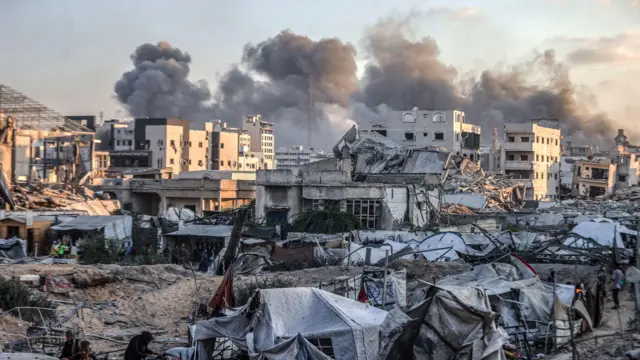 دخان يتصاعد إثر غارات إسرائيلية أصابت ودمرت مبانٍ وأبراج شاهقة في مدينة غزة بالقرب من خيام تؤوي نازحين