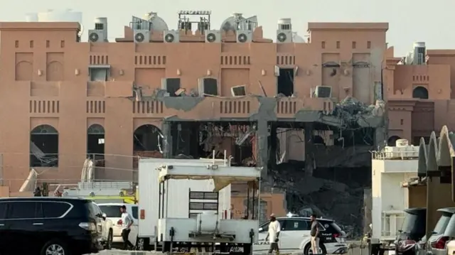 مبنى مدمر الواجهة وتقف أمامه سيارات وحراسة.