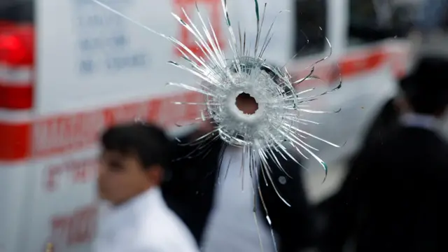 صورة تُظهر ثقباً في زجاج حافلة أحدثته رصاصة.