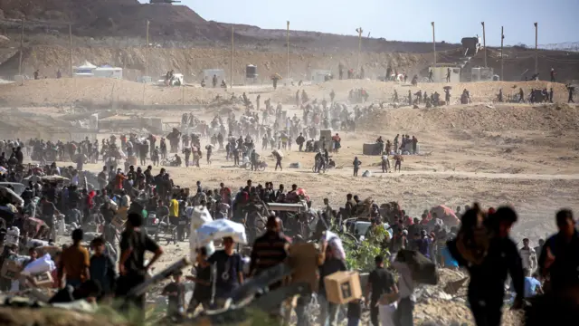  يسير الناس حاملين طرود مساعدات إنسانية تلقوها من مركز توزيع تديره مؤسسة غزة الإنسانية (GHF)، المدعومة من الولايات المتحدة وإسرائيل، في ما يُعرف بـ"ممر نتساريم"، في النصيرات، وسط قطاع غزة، في 30 سبتمبر/أيلول 2025