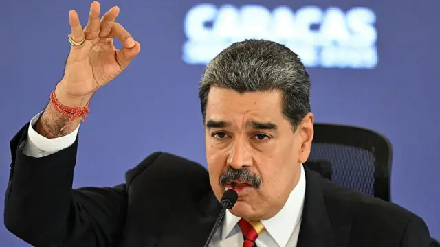 رئيس فنزويلا نيكولاس مادورو يخطب في جمهور رافعاً يده 