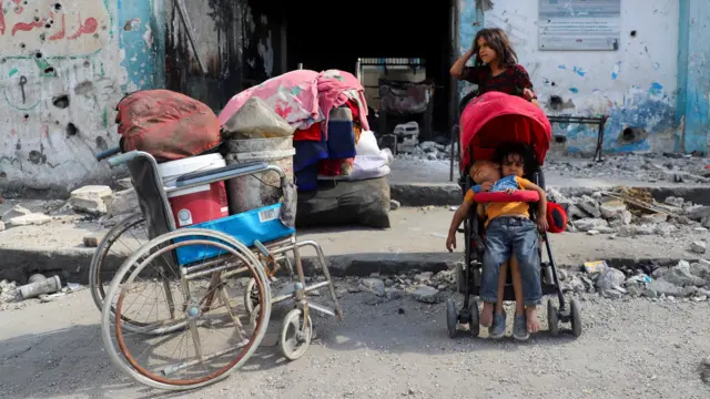 فتاة تقف بجوار عربة أطفال، ويجلس فيها طفلان، بينما يستعد الفلسطينيون النازحون للفرار، وسط عملية عسكرية إسرائيلية، بعد أن أمرت القوات الإسرائيلية سكان مدينة غزة بالإخلاء إلى الجنوب، في مدينة غزة