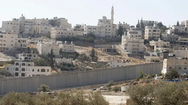 بلدة العيزرية الفلسطينية قرب القدس والجدار الذي بنته الحكومة الإسرائيلية وتعتزم بناء مستوطنة يهودية خلفه، ضمن مشروع إي 1 الاستيطاني، الذي أثار استنكارا دوليا واسعا