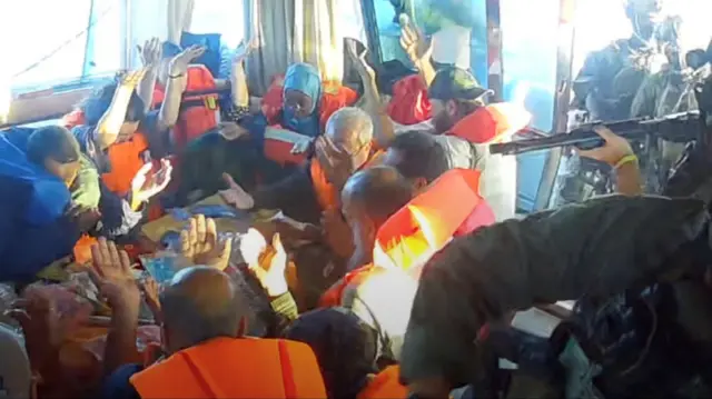 أفراد أسطول الصمود يرفعون أيديهم بعد أن صعدت قوات البحرية الإسرائيلية على متن سفينة "فلوريدا" المتجهة إلى غزة