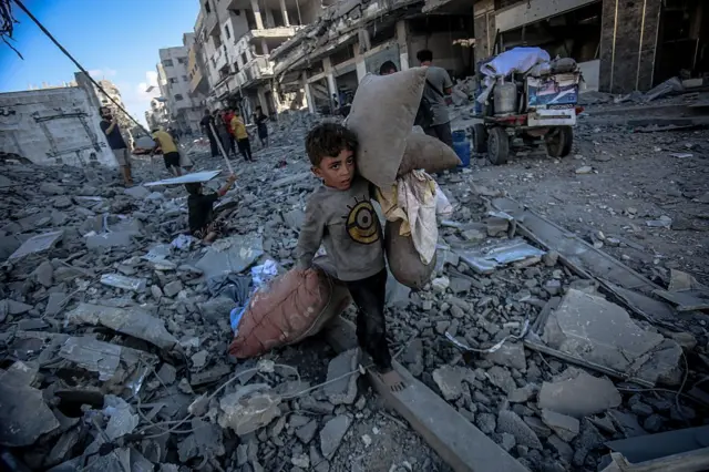 أطفال فلسطينيون يجمعون أغراضهم من بين الأنقاض بعد الغارة الإسرائيلية على شارع أبو حصيرة في مدينة غزة، في 30 سبتمبر/أيلول 2025. 