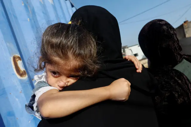 طفلة فلسطينية على كتف أمها، ويظهر عليها التعب