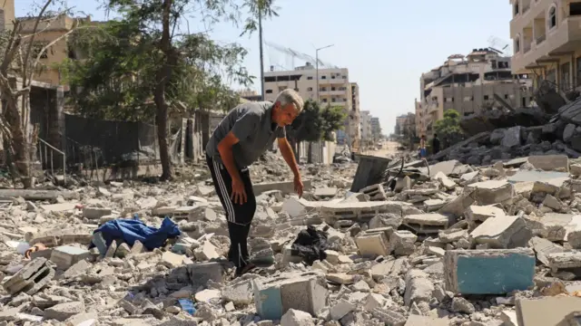 رجل فلسطيني يتفقد الأضرار التي لحقت بمنطقة سكنية، في أعقاب عملية إسرائيلية في المنطقة، بعد أن وافقت حماس على إطلاق سراح الرهائن وقبول بعض الشروط الأخرى في خطة أمريكية لإنهاء الحرب، في مدينة غزة، 4 أكتوبر/تشرين الأول.