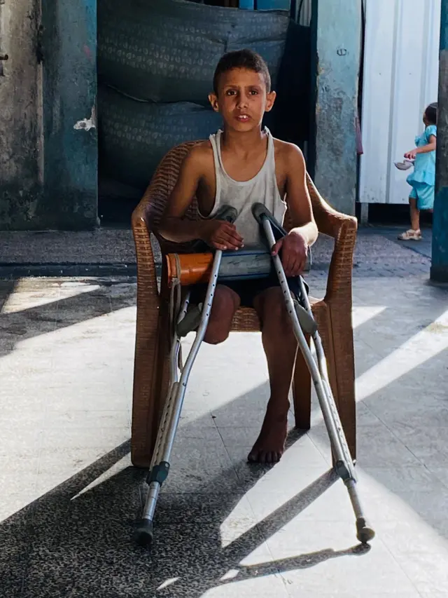 جالساً على كرسي ويحمل أنبوباً بلاستيكياً