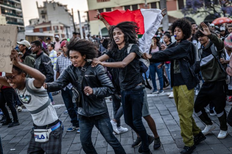 TOPSHOT - Young residents hold banners and flags while dancing to rock music during a concert as crowds gather for a civil society rally demanding President Rajoelina’s resignation, following the announcement by Madagascar’s Army CAPSAT unit that they would assume power in the country in Antananarivo, October 14, 2025.