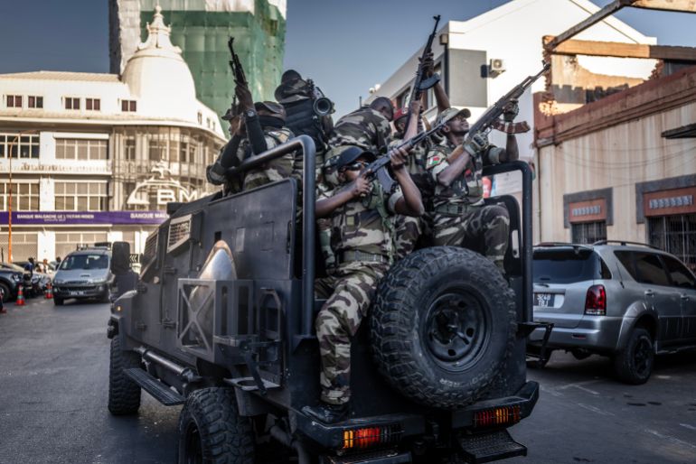 TOPSHOT - Members of Madagascar’s Army CAPSAT unit ride in armoured vehicles while assuming a defensive posture as they leave the Presidential Palace in Antananarivo, October 14, 2025.