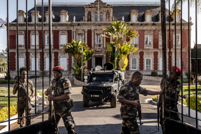 TOPSHOT - Members of the Madagascar CAPSAT military open the gates of the presidential palace in Antananarivo on October 14, 2025 before Colonel Michael Randrianirina (C), head of the CAPSAT military unit, announced that they will take power in the country.
