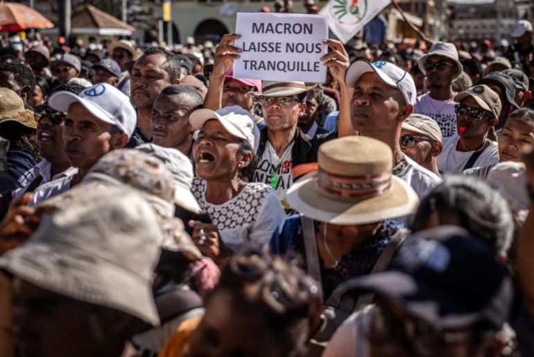 A protester holds a banner critical of France’s President Emmanuel Macron as residents gather for a civil society rally demanding the resignation of Madagascar’s President Andry Rajoelina in Antananarivo, on October 14, 2025.