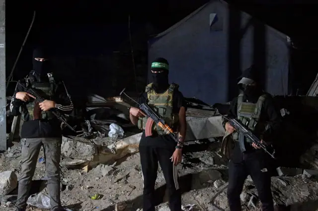 مقاتلون فلسطينيون من كتائب عز الدين القسام التابعة لحماس يحرسون وصول مركبات اللجنة الدولية للصليب الأحمر لنقل رفات الرهائن الإسرائيليين الذين سلمتهم حماس في مدينة غزة، 15 أكتوبر 2025.
