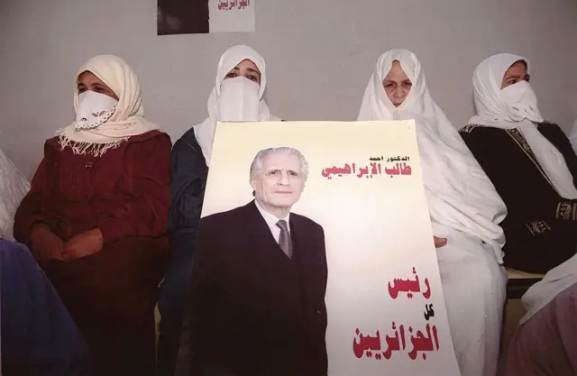 مناصرات لأحمد طالب الإبراهيمي، المرشح المستقل إلى رئاسة الجمهورية، يحملن ملصقاً انتخابياً في 10 أبريل/نيسان 1999 في مدينة عين الدفلى (غرب الجزائر).