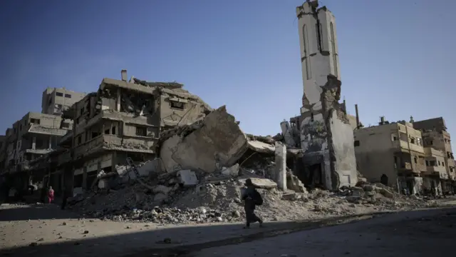 امرأة فلسطينية تسير بجوار مسجد ومنازل مدمرة بعد غارة جوية إسرائيلية خلال عملية عسكرية إسرائيلية في مدينة غزة، قطاع غزة