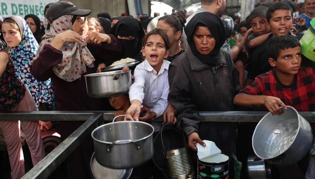 فلسطينيون يحاولون الحصول على حصص غذائية في مخيم النصيرات للاجئين، وسط قطاع غزة. (أ ف ب)